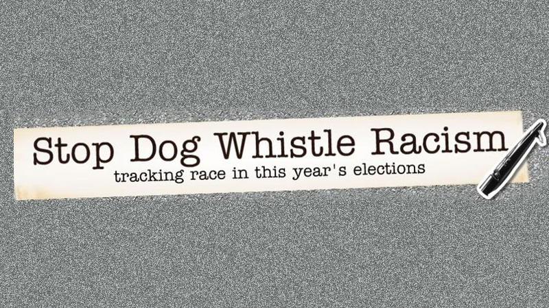 Tiny slip of weathered paper that reads "Stop Dog Whistle Racism" on a static black, white and gray background
