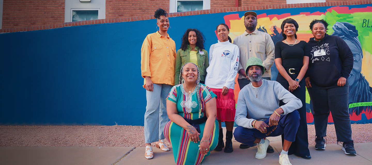 Outdoor group photo of nine artists and culture bearers, who are participating in our 2024 Housing, Land, and Justice Artist (HLJA) Fellowship