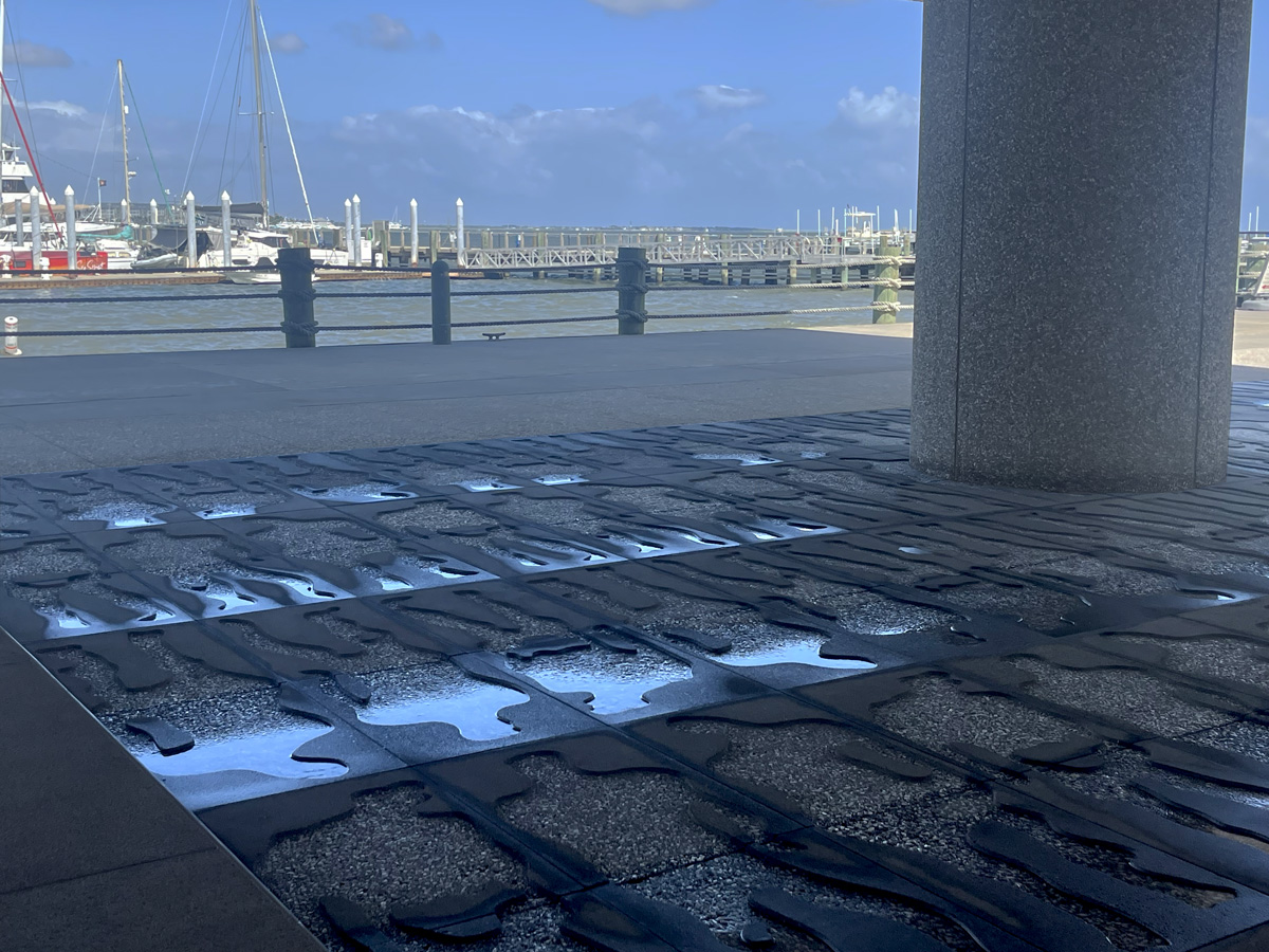 Museum ground with water-filled full body silhouettes embedded in the pavement.