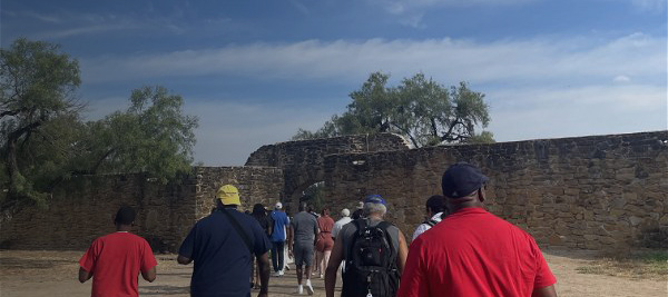 People walking toward entryway in stone wall.